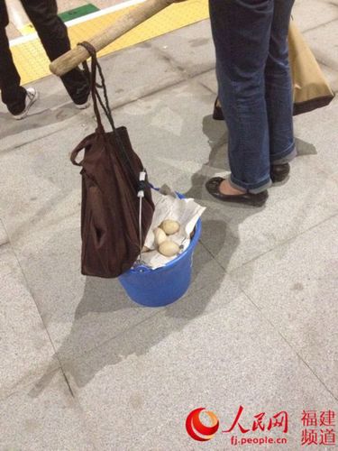一位夜里在漳浦动车站等车的母亲，她挑两桶蛋去厦门给儿子。林长生 摄