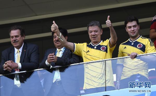 6月19日，哥伦比亚总统桑托斯（右二）现场观战时为球队加油助威。当日，在巴西首都巴西利亚马内•加林查国家体育场进行的2014年巴西世界杯小组赛C组比赛中，哥伦比亚队对阵科特迪瓦队。 新华社记者戚恒摄