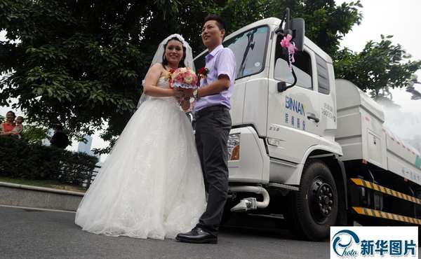 05 2014年8月15日，重庆，一对新人结婚用12辆环卫车洒水迎亲。新郎新娘在洒水车前合影。