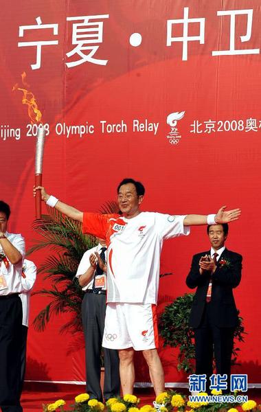 2008年6月29日，北京奥运圣火在宁夏中卫传递，火炬手张贤亮在起跑仪式上高举火炬。