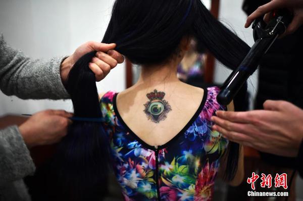 　一位举牌女郎后背上的纹身。中新社发 稻草 摄 图片来源：CNSPHOTO