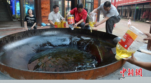 　图为工作人员向大铁锅加入食用油。