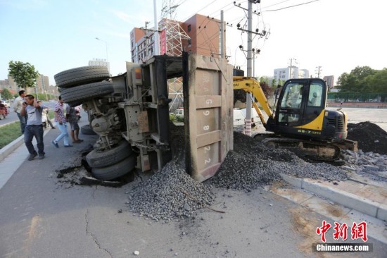 图为一辆满载建筑材料的渣土车途径此处路面突然塌陷造成车辆侧翻。 杨正华 摄