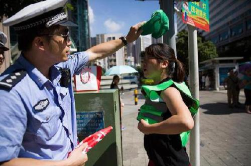 图为一位女子闯红灯被抓，很配合地穿上了绿马甲，交警帮忙戴上绿帽子。