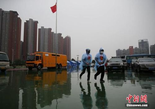 8月18日，天津泰达二小安置点内的两名志愿者跑回楼内避雨。当日10时，天津港“8·12”特别重大火灾爆炸事故所在区域下起中雨。中新社发 杨可佳 摄
