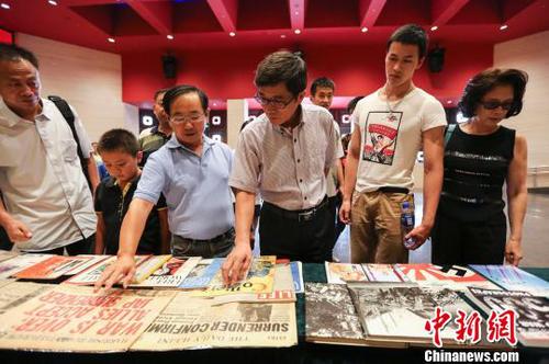 9月1日，美籍华人鲁照宁（左二）向中国人民抗日战争纪念馆捐赠报纸、期刊、宣传册、照片、纪念邮票、书籍等30余件抗战史料。图为他向该馆副馆长李宗远（左三）讲解他所收集的文物资料。　熊然　摄