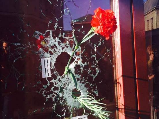 袭击现场可以看到酒吧窗户玻璃上有子弹射击留下的弹孔，弹孔里被前来悼念的巴黎市民插入了鲜花。