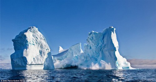 当时，摄影师Alexander Perov正打算拍摄一艘小艇穿越冰山拱洞的照片，结果巨大的冰块突然从冰山上脱离坠落，激起滔天巨浪，让正在附近的小艇急忙快速躲避。