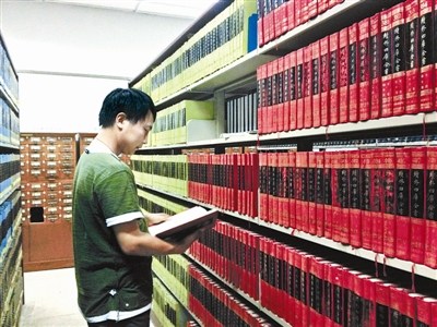 资料图：一名古籍爱好者正在北大古籍阅览室翻看“四库全书”。图片来源：北京青年报