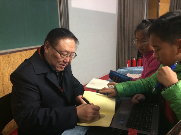 在三月二十二日北京中关村第一小学的读书活动上，著名作家高洪波委员给小学生签名