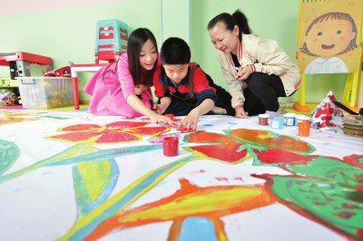 志愿者正在指导自闭症儿童在长卷上进行绘画创作