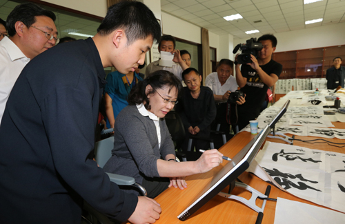 　图为张海迪主席到北京市怀柔区残疾人职业康复中心考察工作并体验书法学习软件