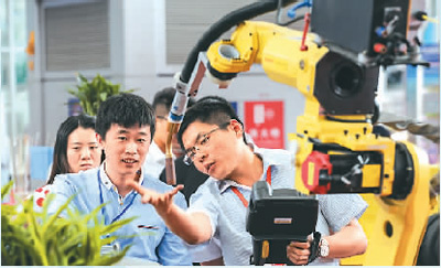 近日，在哈尔滨国际装备制造业博览会上，一家参展企业工作人员（右）在介绍机械臂。新华社记者 王 松摄