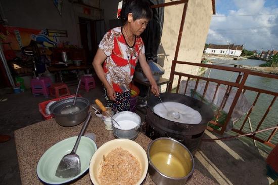　5月27日，埭美村一位经营小吃店的村民在为游客做当地美食“锅边糊”