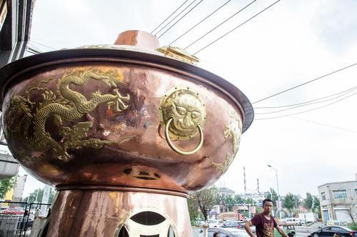 2016年7月29日，吉林，解放路某火锅店门前一个硕大的火锅吸引了市民的目光。这个大约两层楼高的大火锅全身金黄色，上面有两条金龙，十分壮观。