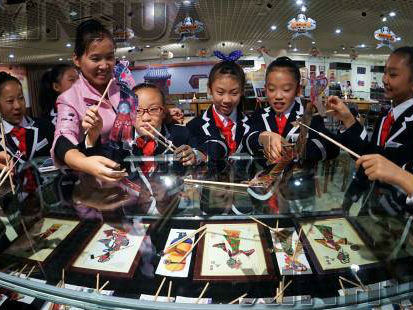 皮影传承人王熙（右六）在潘家园旧货市场文化展厅教小学生表演皮影。 新华社记者 李欣 摄