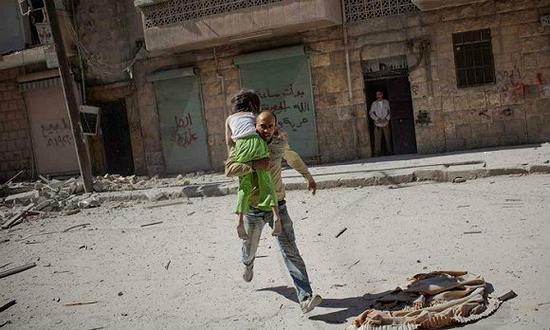　　“你需要关注你的头脑和你的心灵”。2012年，为逃避空袭阿勒波（叙利亚）的导弹，一个父亲带着他的女儿跑出公寓。摄影师：尼科尔·唐