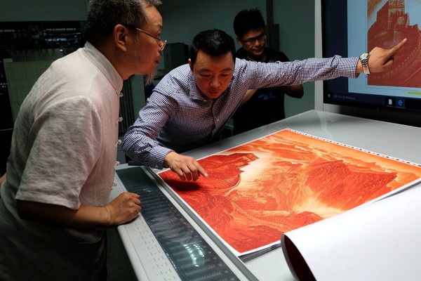 印刷负责人向《万里长城》铜版画作者许仁龙介绍初步上色的画面效果