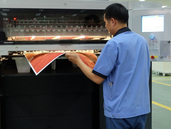 印刷技师将《许仁龙万里长城铜版画》画框产品从印刷设备中取出