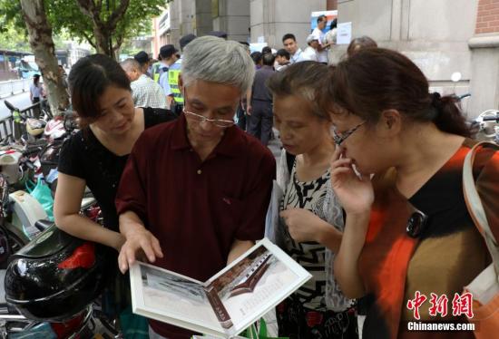 资料图：几位杭州市民欣赏已买到的“G20杭州峰会明信片”。 中新社记者 王刚 摄