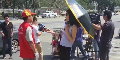厦门一女记者戴墨镜打伞采访救灾志愿者