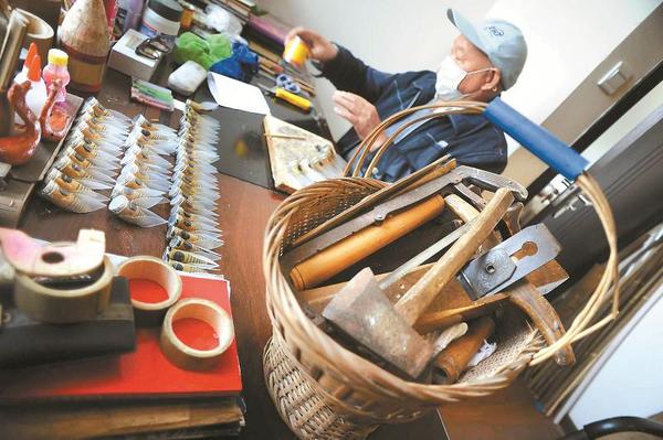 一个篮子里装满了各种制作工具，其中有不少是万富册老人自己设计制作的。