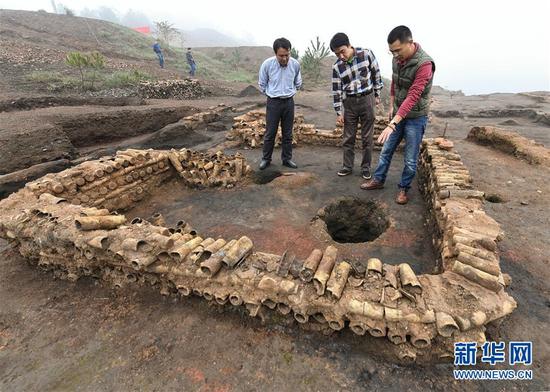 在桐木岭矿冶遗址，考古人员查看用废弃坩埚垒筑的房屋遗址（11月18日摄）。