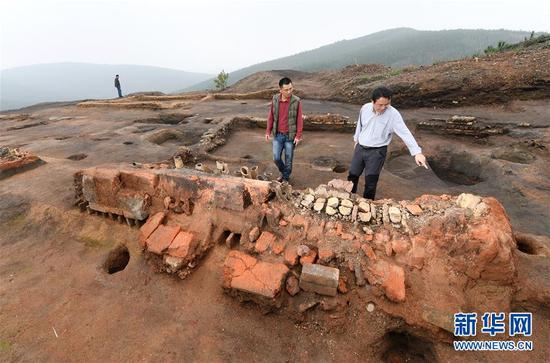 在桐木岭矿冶遗址，考古工作者在查看一个槽形冶炼炉（11月18日摄）。