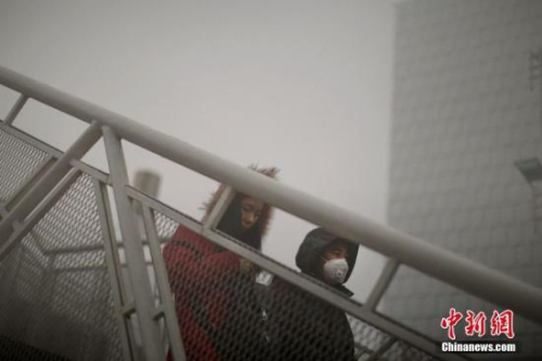 12月4日，戴着口罩的行人从天桥上走过。天津市气象台当日7时发布大雾橙色预警信号，天津大部分地区笼罩在大雾中，局部地区能见度低于200米。 <a target='_blank' href='http://www.chinanews.com/'>中新社</a>记者 佟郁 摄