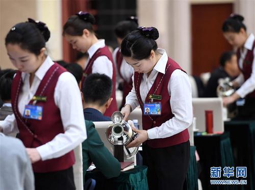 3月6日，北京华北宾馆的女服务员在民盟、无党派人士界委员联组会上倒水。在两会会场内外，女代表、女委员、女工作人员、女记者在工作中尽职尽责，展现着自己的风采。 新华社记者张铎摄