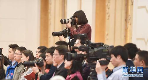 3月7日，一名女记者在十二届全国人大五次会议江苏代表团全体会议上采访拍摄。在两会会场内外，女代表、女委员、女工作人员、女记者在工作中尽职尽责，展现着自己的风采。 新华社记者陈晔华摄