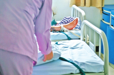 一位病人沉沉睡去，护士还在为另一位病人整理床铺。