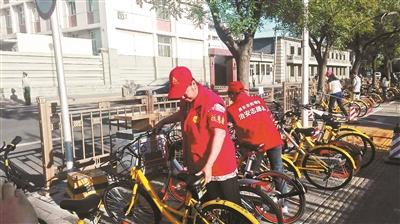 西长安街街道志愿者将共享单车码放整齐