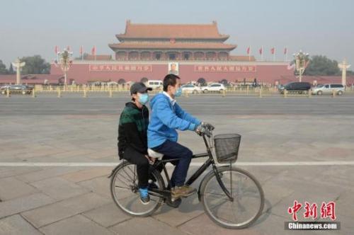 资料图：一对青年佩戴口罩骑车经过北京天安门广场。 <a target='_blank' href='http://www.chinanews.com/'>中新社</a>记者 崔楠 摄