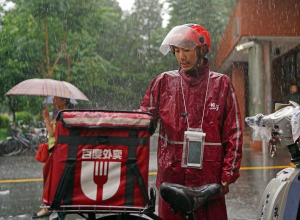 外卖送货员在暴雨中坚持工作。新华社记者陈诚摄