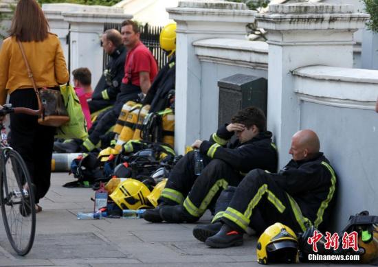 6月14日，伦敦西部一栋24层的公寓楼发生大火，火势猛烈，蔓延到了所有楼层。目前这场火灾已造成超过50人受伤。图为疲惫的消防员在路边休息。 <a target='_blank' href='http://www.chinanews.com/'>中新社</a>记者 周兆军 摄