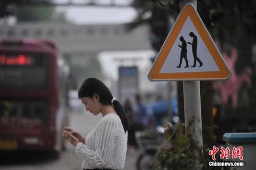 重庆涪陵红酒小镇一红绿灯处摆放了“不做低头族、关注红绿灯”警示牌，提醒市民在过斑马线的时候不能玩手机，注意交通安全。 陈超 摄