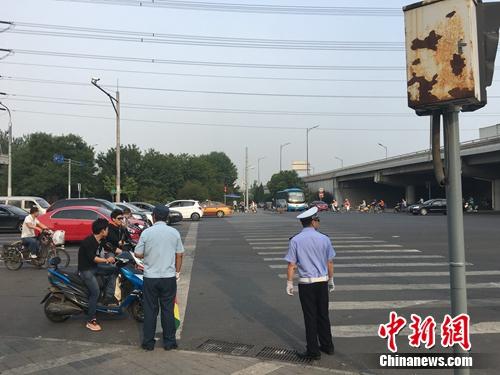 6月21日上午，北京仰山桥下十字路口，执勤人员要求非机动车停在停止线后。汤琪 摄