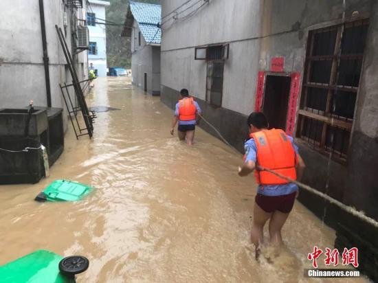 图为浙江省丽水市遂昌县民警在积水中准备营救居民。