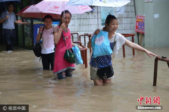 图为南京市雨花台区，市民在水中艰难出行。图片来源：视觉中国