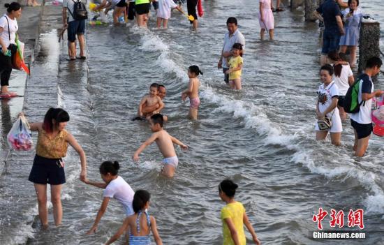 7月4日傍晚，市民们带着小孩在海边戏水消暑。连日来，受副热带高压影响厦门地区持续高温。 张斌 摄