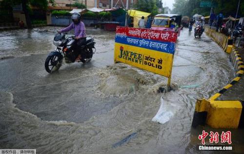 印度民众经过水淹的街道。