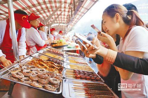 北京一“虫子宴”摊位，摆满串蛇、蜈蚣、蚂蚱、蜘蛛等，不少食客拿出手机拍照。（台湾中时电子报）