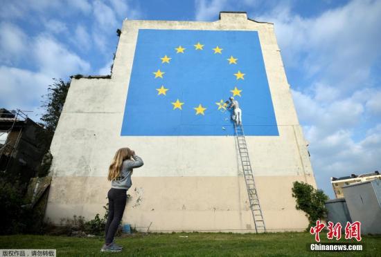当地时间2017年5月7日，英国多佛，一名街头艺术家班克西创作了一幅画，画面中一名工人正从欧盟12星旗帜上抹掉一颗星，寓意着英国将脱离欧盟。