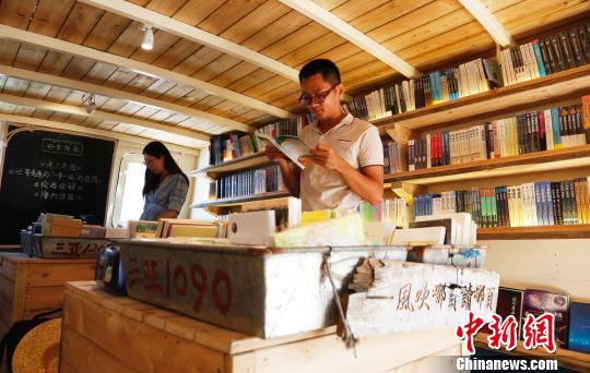 9月5日，海南三亚西岛渔村“海上书房”，桌上传统装鱼的盆被用来放书，年轻人在翻看书籍。　尹海明 摄