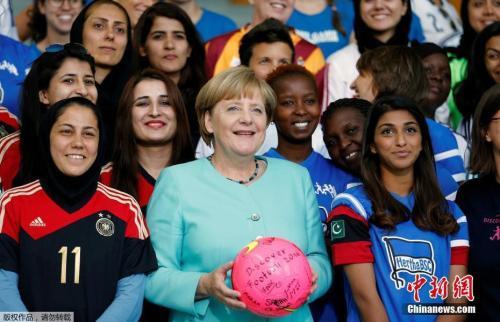 资料图：德国总理默克尔会见女子足球联赛的选手，并收获签名足球。