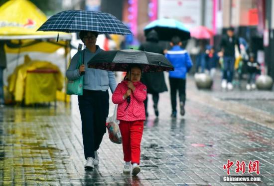 资料图：9月24日，新疆乌鲁木齐市降下秋雨，外出民众打着雨伞快步前行。 <a target='_blank' href='http://www.chinanews.com/'>中新社</a>记者 刘新 摄
