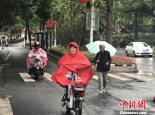 11日，南京迎来降温降雨。图为市民披上雨衣出行。　杨颜慈 摄