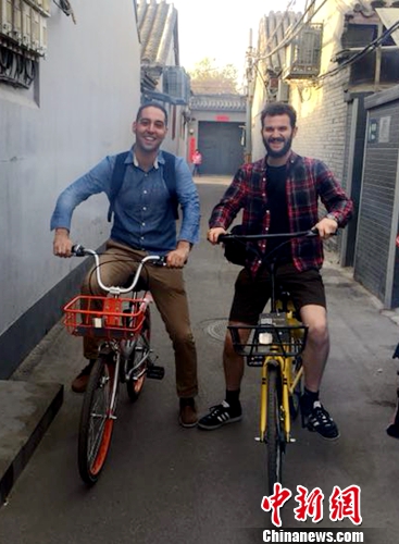 英国人Chris Georgiou(左)和朋友在北京骑共享单车逛胡同。受访者供图