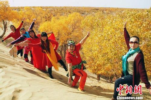 10月21日，在新疆尉犁县塔里木河沿岸胡杨林“披黄挂金”吸引游客拍美照。　杨厚伟 摄
